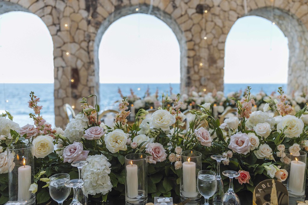 Floral tablescape under stone arches overlooking the sea